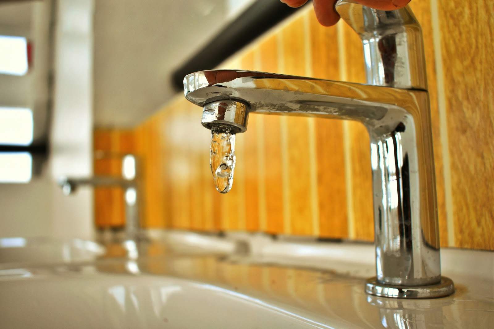 Silver bathroom faucet with water dripping out.