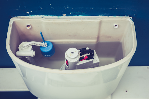 A toilet tank with the lid removed.