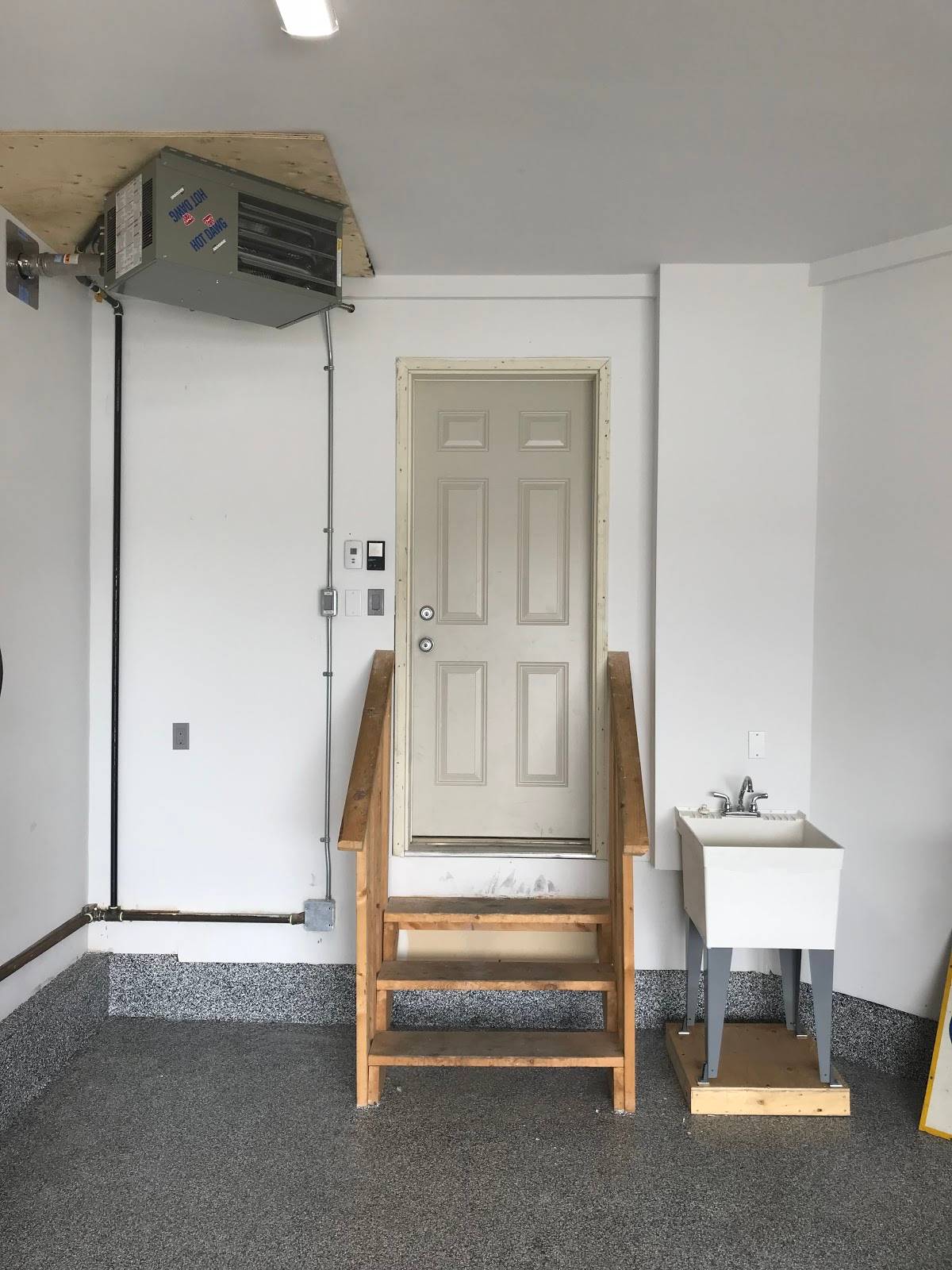 The interior of a garage with wooden stairs leading up to a white door.