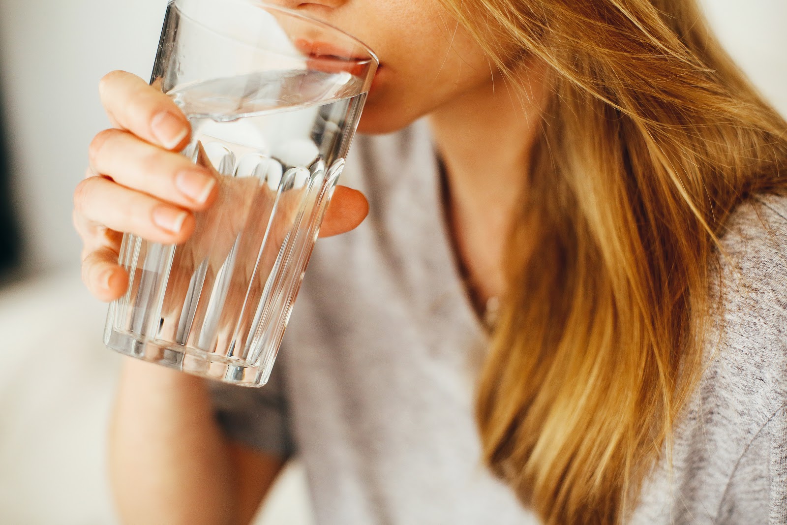 Woman drinking water out of a clear glass.