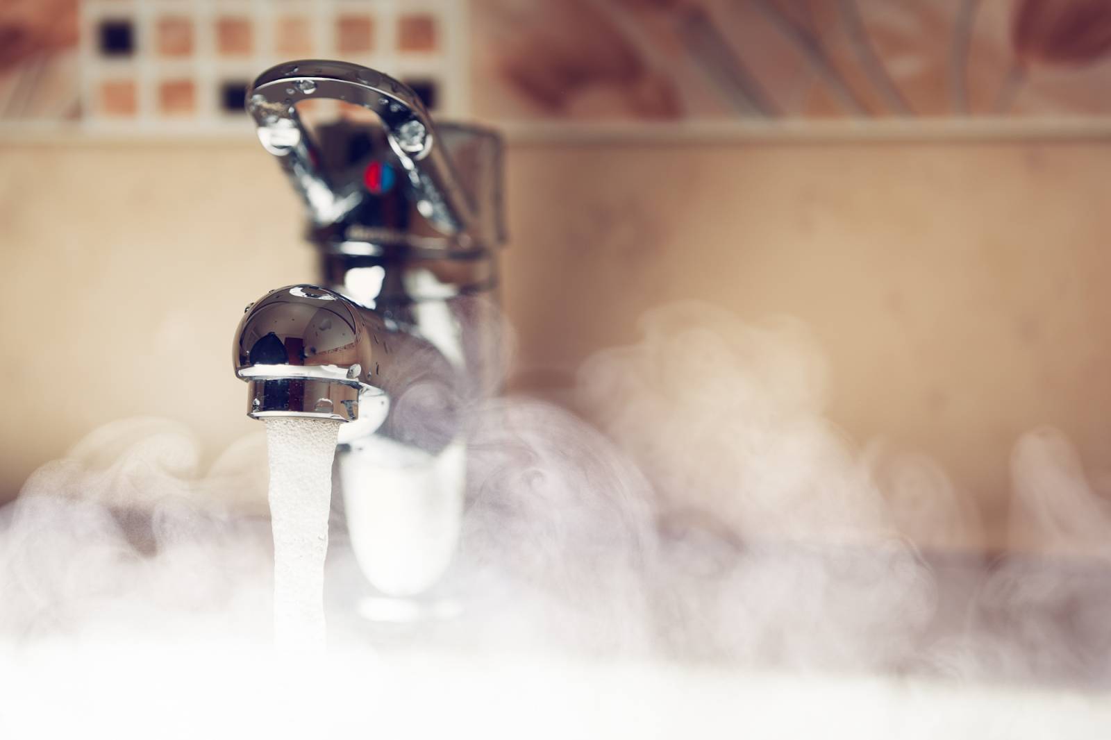 A faucet with hot water running and steam rising up.