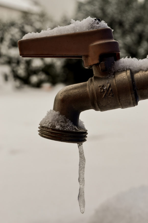 Outdoor faucet with ice coming out of it and a snowy background