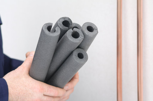 Hands holding grey foam pipe insulation.